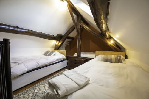Chambre mansardée au Domaine Chapelle avec poutres apparentes, deux lits, draps blancs et vue sur le jardin