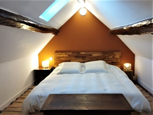 Chambre mansardée douillette au Domaine Chapelle B&B avec lit queen, poutres en bois, éclairage chaleureux et lucarnes donnant sur le jardin