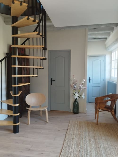 Escalier spiralé moderne dans la lumineuse salle Domaine Chapelle avec chaises en bois, portes blanches et vue sur le jardin, La