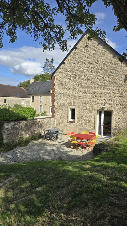 Maison en pierre avec mobilier de jardin rouge au gîte Domaine de la Cour VAUTIER à Mandeville-en-Bessin, Normandie