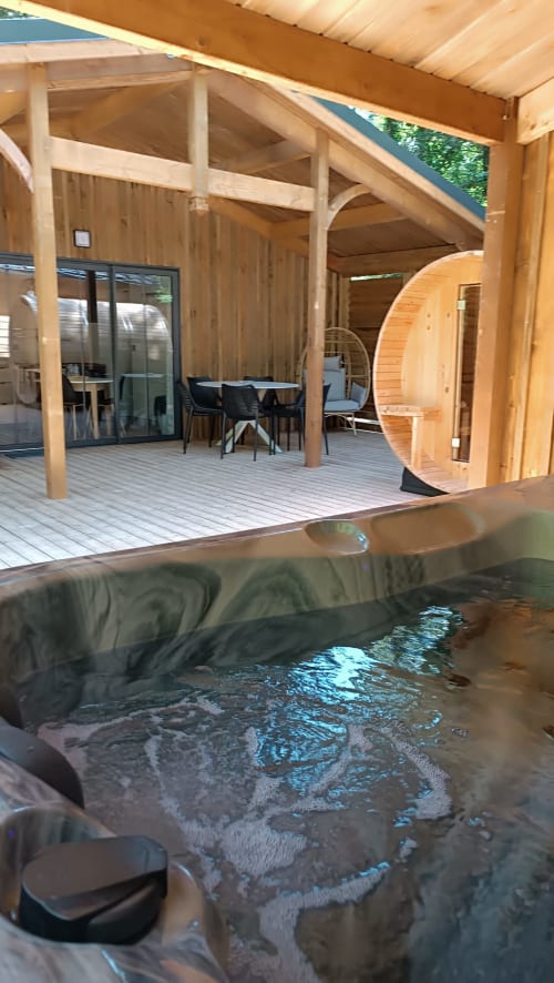 Spa balnéo sur terrasse en bois de la villa Les Chalets Du Lac avec salon et salle à manger, Marange-Silvange