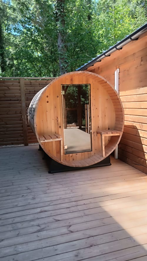 Sauna en tonneau en bois sur la terrasse de la villa Les Chalets Du Lac à Marange-Silvange, avec vue sur la forêt