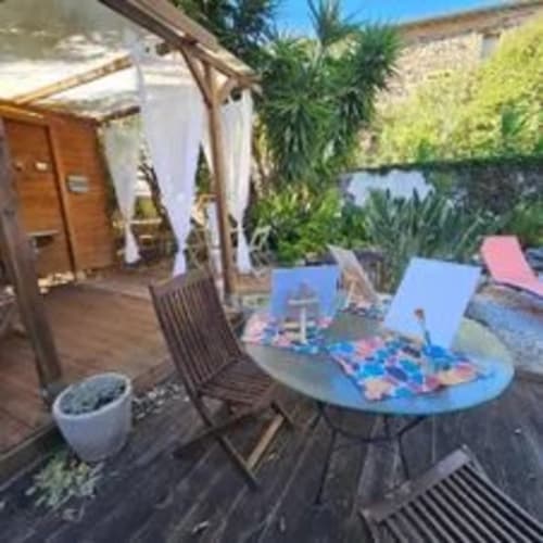 Patio ensoleillé de la Maison D'hôtes Coeur D'hérault avec chaises longues, tables bleues, pergola et plantes luxuriantes