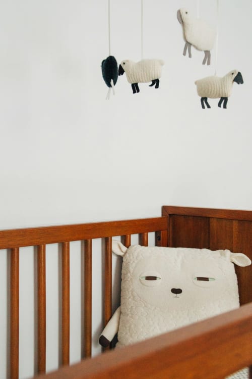 Cuna de madera en Hostal Restaurante Angel con móvil de ovejitas tejidas y juguete de peluche