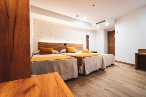 Habitación triple del Hostal Restaurante Angel en Huelma con dos camas, muebles de madera, iluminación cálida y comodidades modernas