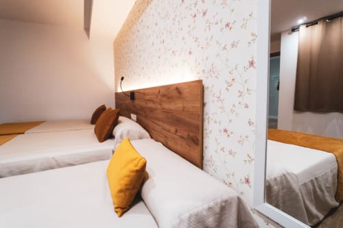 Habitación triple en Hostal Restaurante Angel con camas gemelas, papel tapiz floral, cabecero de madera y almohada amarilla