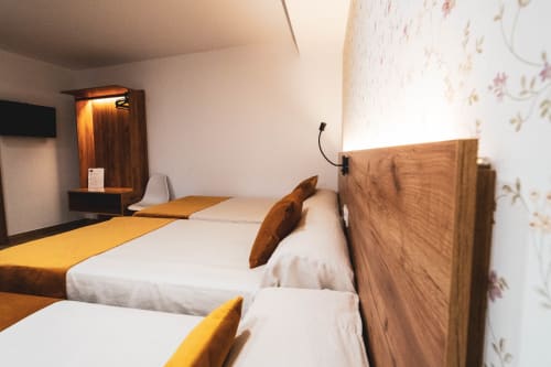 Habitación triple del Hostal Restaurante Angel en Huelma con camas gemelas, cabeceros de madera, detalles en amarillo y estante flotante