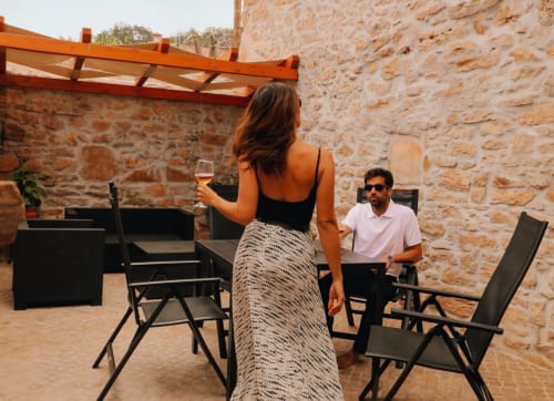 Mulher com vinho e homem relaxando no pátio de pedra do hotel Recantos D'Almerinda em Pombal, Portugal