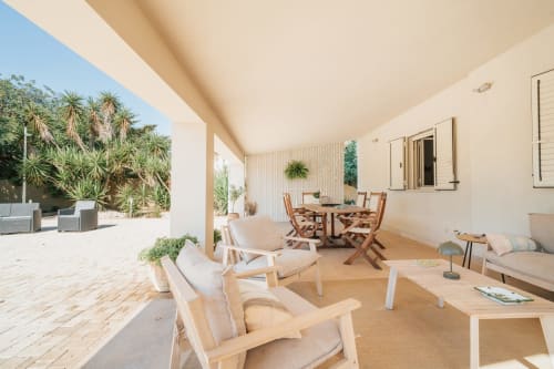 Ampia veranda coperta a Case Luparello a Noto con arredamento in legno, lettini relax, zona pranzo e vista sul giardino lussureggiante