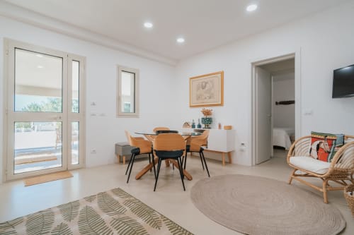 Soggiorno moderno nell'appartamento Biancolilla a Case Luparello, Noto, con zona pranzo, porte con vista sul giardino e stile contemporaneo