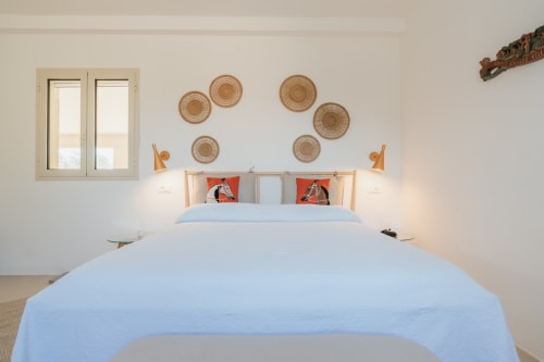 Camera luminosa a Case Luparello con biancheria blu cielo, letto in legno, cesti intrecciati e vista sul giardino dalla finestra