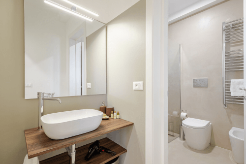 Bagno moderno dell'appartamento Biancolilla a Case Luparello, Noto, con lavabo ovale bianco, mobile in legno e stile contemporaneo