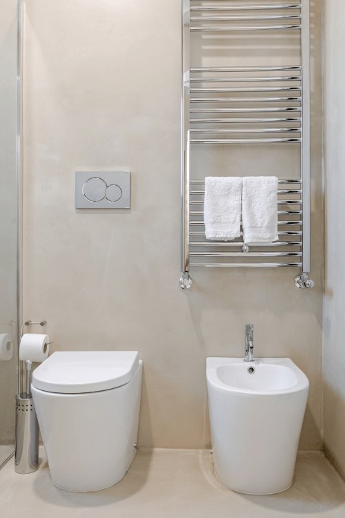 Bagno moderno a Case Luparello Noto con sanitari bianchi, bidet, termoarredo cromato e cassetta a doppio scarico