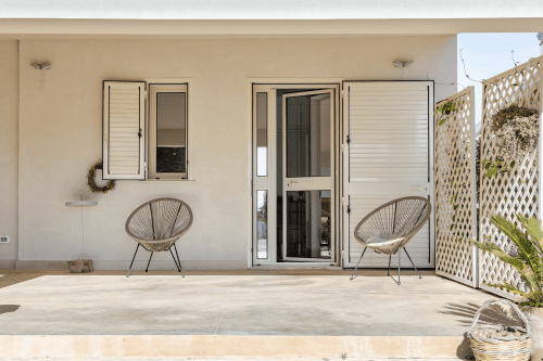 Patio moderno dell'appartamento Case Luparello Noto con sedie intrecciate, zona living esterna privata e vista sul giardino