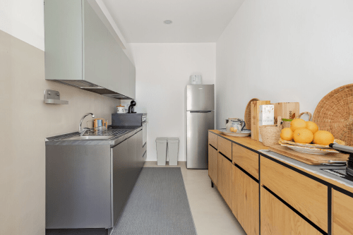 Cucina moderna nell'appartamento Biancolilla a Case Luparello, Noto, con mobili grigi, elettrodomestici in acciaio inox e finiture in legno