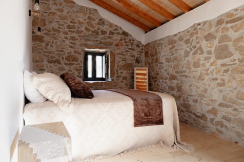 Quarto rústico de pedra em Recantos D'Almerinda em Pombal, Portugal com vigas de madeira e roupas de cama cru