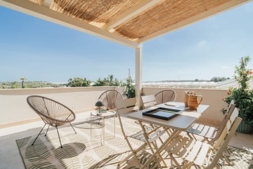 Terrazza dell'appartamento Moresca a Case Luparello, Noto con sedute moderne, tavolo da pranzo e vista sulla campagna sotto struttura in legno