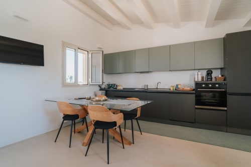 Cucina moderna e zona pranzo dell'appartamento Moresca a Case Luparello, Noto con sedie in legno e mobili scuri