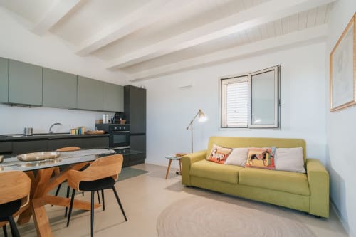 Ampio appartamento open-plan a Case Luparello, Noto con divano verde, cucina, zona pranzo e travi in vista