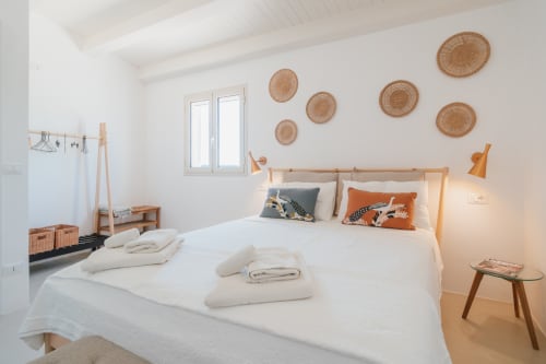 Camera luminosa a Case Luparello a Noto con biancheria bianca, decorazioni murali in vimini e arredamento in legno