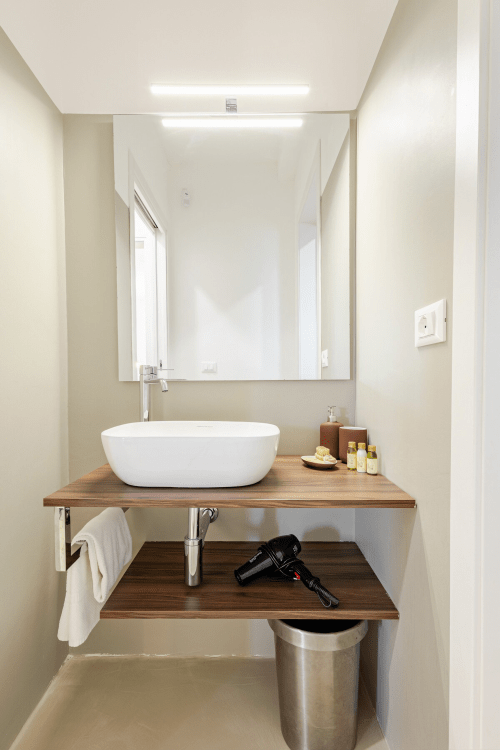 Bagno moderno a Case Luparello, Noto con lavabo ovale bianco, piano in legno e specchio illuminato