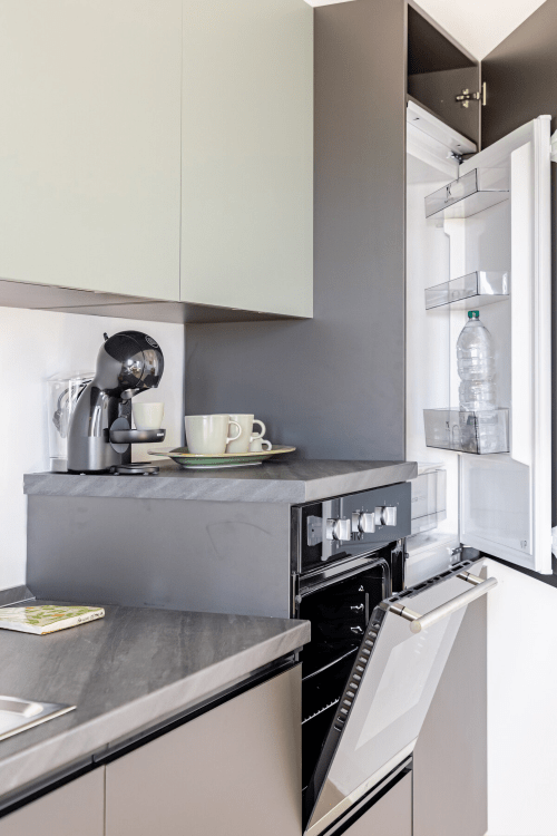 Cucina moderna con piani di lavoro grigi, caffettiera e frigorifero aperto presso Case Luparello, Noto