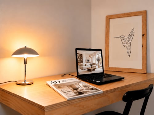 Spazio di lavoro moderno presso Easystay Bari con scrivania in legno, lampada, laptop, rivista e arte murale geometrica di colibrì