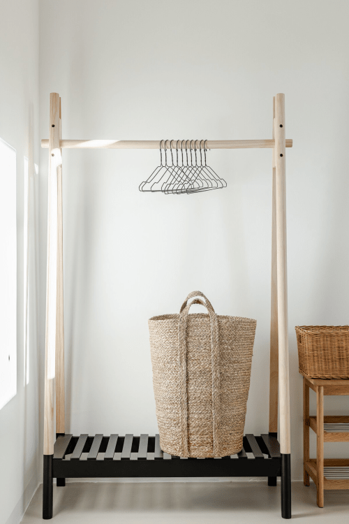 Appendiabiti in legno minimalista con grucce metalliche e cesto intrecciato a Case Luparello, Noto