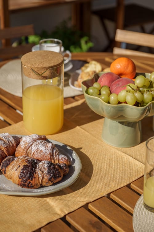 Colazione a Case Luparello con cornetti, frutta fresca, succo d'arancia e pasticcini su tavolo in legno