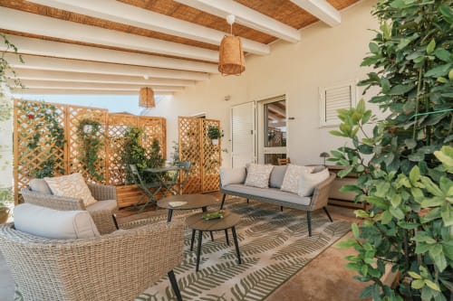 Terrazza con vista sul giardino di Case Luparello a Noto: mobili in vimini, piante in vaso e schermi in legno