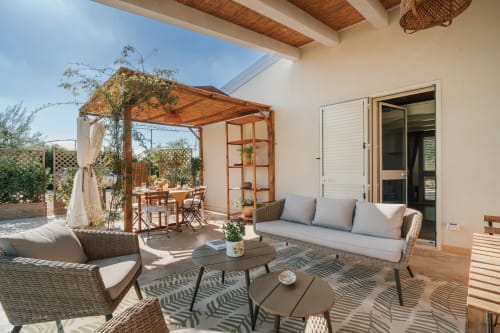 Terrazza giardino Carolea di Case Luparello a Noto con sedute in vimini, pergolato e zona pranzo