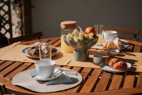Tavola della colazione a Case Luparello a Noto con dolci, frutta, caffè e vista sul giardino nell'appartamento Carolea