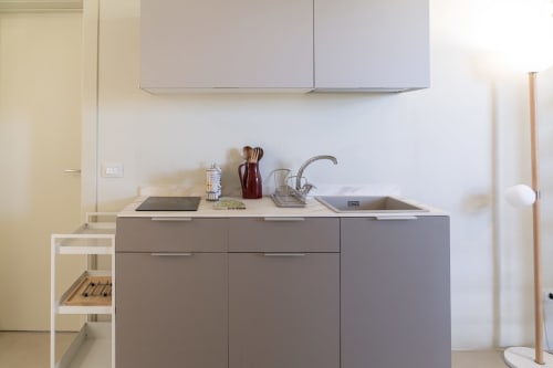 Piccola cucina moderna nell'appartamento Carolea di Case Luparello a Noto con mobili grigio e piano cottura
