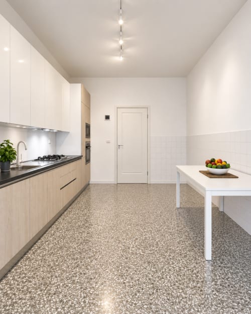 Cucina moderna nell'Easystay Bari Apartment con armadi in legno chiaro, muri bianchi, pavimento in terrazzo e tavolo da pranzo