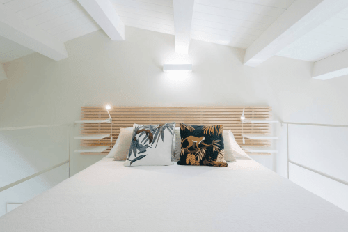 Camera da letto luminosa nell'appartamento Carolea di Case Luparello, Noto con testata in legno e cuscini decorativi