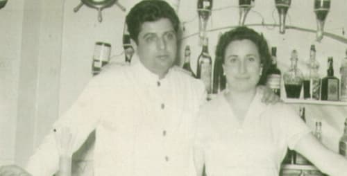 Dos camareros con uniformes blancos detrás de la barra del Hotel La Muntanya en Llafranc