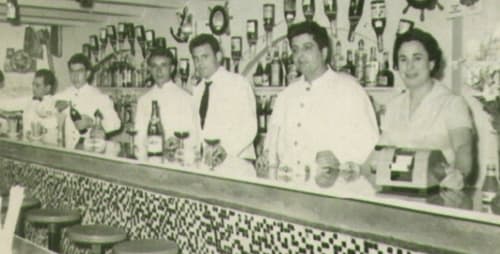 Escena vintage en el bar del Hotel La Muntanya en Llafranc con personal y clientes tras la barra