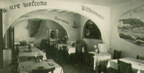 Comedor vintage del Hotel La Muntanya en Llafranc con arcos, texto de bienvenida y vistas montañosas en las paredes