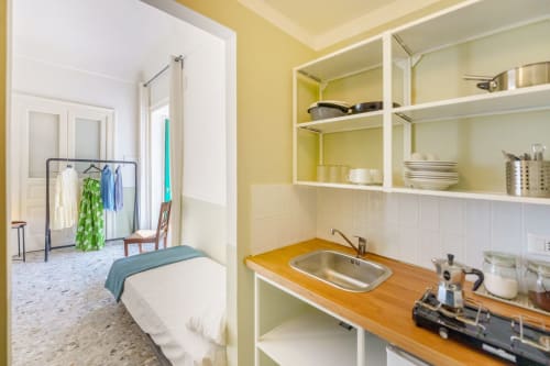 Angolo cottura dell'appartamento B&B Oliveri 25 con bancone in legno, lavello, pareti gialle e ripiani bianchi a Procida