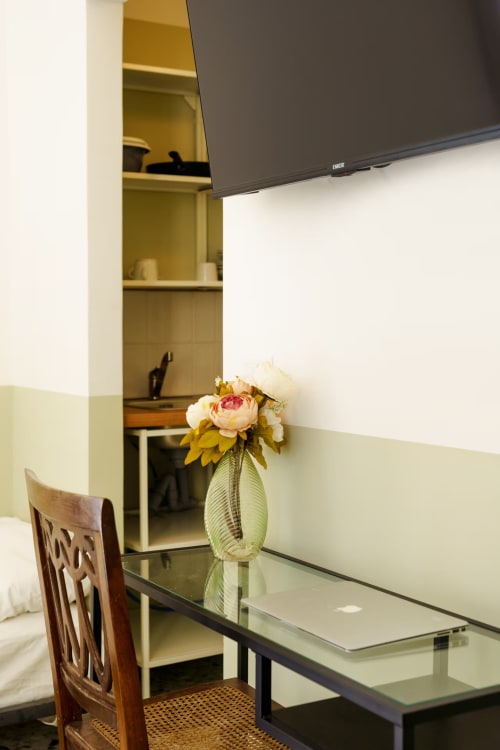 Moderno spazio di lavoro con scrivania, composizione floreale, TV a parete e scaffali integrati presso B&B Oliveri 25, Procida