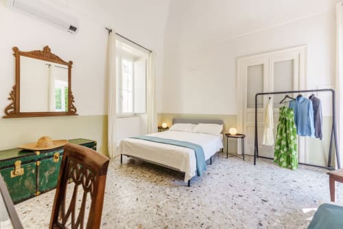 Spaziosa camera da letto con vista mare presso B&B Oliveri 25 a Procida, con biancheria bianca, mobili in legno e pavimento in terrazzo