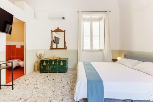 Camera da letto del B&B Oliveri 25 a Procida con vista mare, letto, baule vintage e pavimento in terrazzo