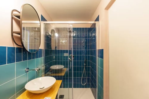 Bagno moderno della B&B Oliveri 25 a Procida con piastrelle blu-turchese, lavandino bianco e box doccia in vetro