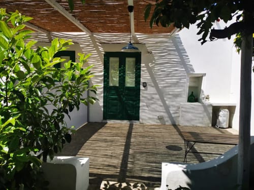 Ingresso al patio ombreggiato dell'Appartamento 2 presso il B&B Oliveri 25, Procida con porte verdi e pavimento in legno
