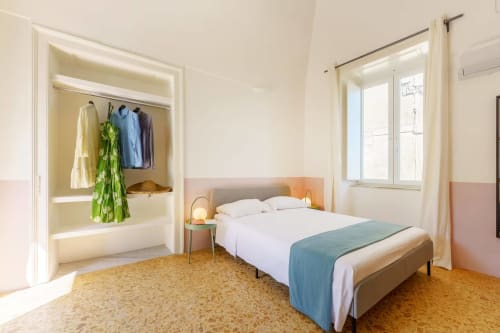 Camera moderna al B&B Oliveri 25 di Procida con letto, armadio aperto, pavimento in sughero e finestre con vista sul mare