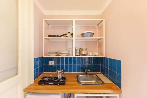 Cucina compatta nell'appartamento B&B Oliveri 25 a Procida con bancone in legno, piastrelle blu in fondo e ripiani aperti