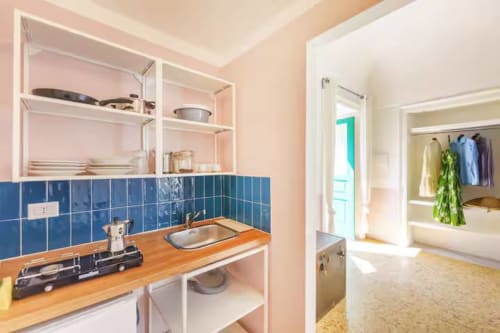 Cucina dell'appartamento B&B Oliveri 25 con alzatile in piastrelle blu, bancone in legno e scaffali aperti a Procida