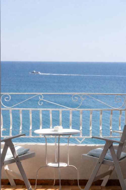 Balcone con vista sul mare di Villa Bina Sea Hotel, sedie a righe e tavolo con affaccio sul Mediterraneo e nave in transito