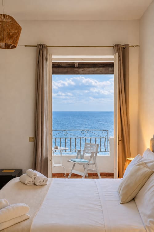 Luminosa camera Superior con balcone vista mare presso Villa Bina Sea Hotel, letto bianco con asciugamani arrotolati affacciato sul Mar Tirreno