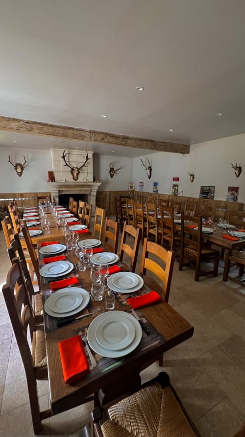 Salle à manger élégante du Cloffy B&B à Nouans-les-Fontaines avec longues tables en bois, serviettes rouges et décoration de bois de cerfs.